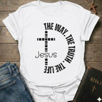 White t-shirt with a cross and text  "Jesus The Way The Truth The Life Cross Circle John 14:6" Christian faith apparel Faith Forward. It is on a wooden surface with jeans and a Bible.