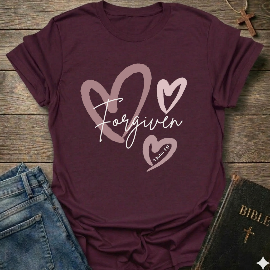 Maroon t-shirt with 'Forgiven' text and pink hearts on a wooden surface with jeans and a Bible. Forgiven Christian T-Shirt 1 John 1:9 bold faith apparel Faith Forward women