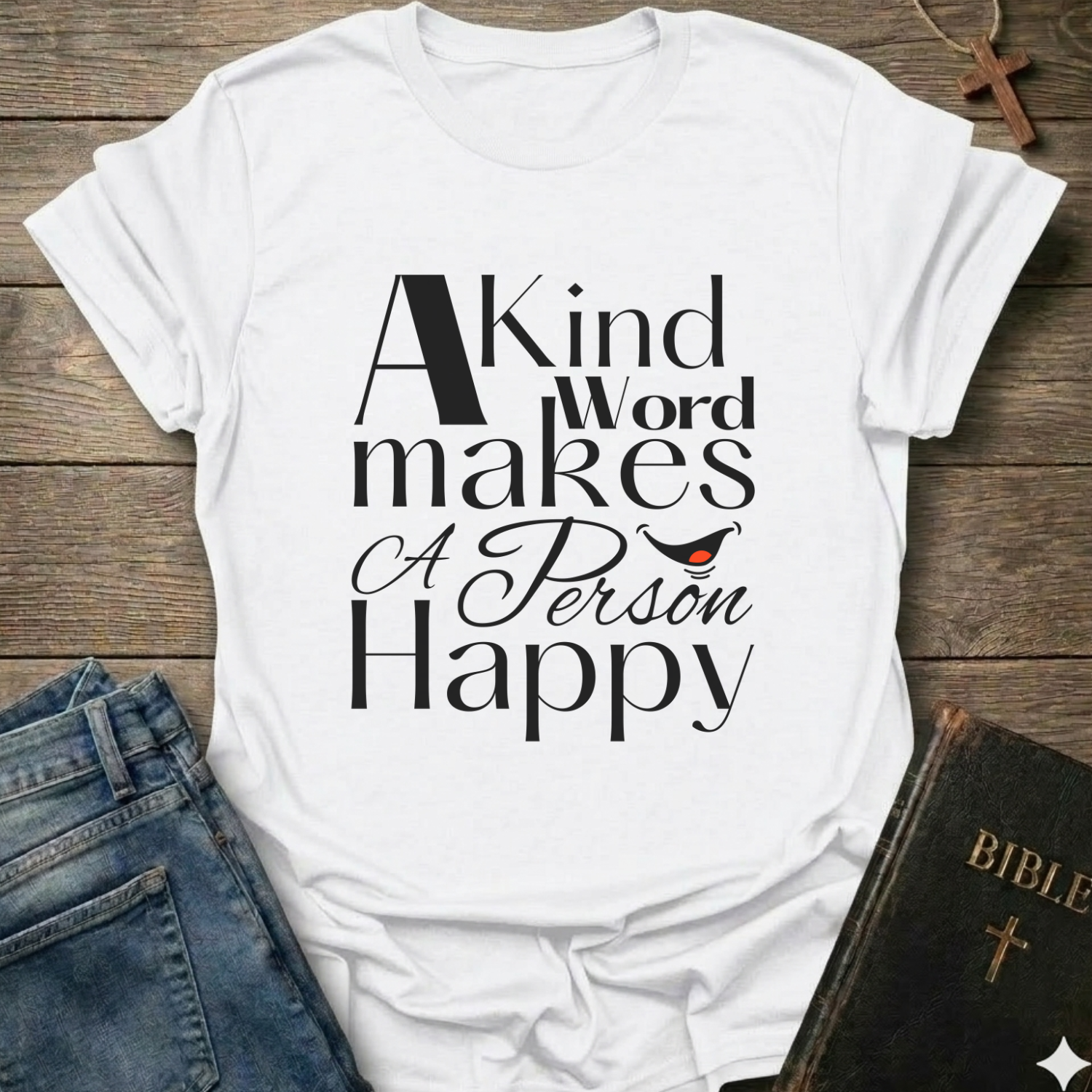 White t-shirt with 'A Kind Word makes A Person Happy' Proverbs 12:25 text with a smile. Christian elegant typography faith apparel conversation starter
on a wooden surface with jeans and a Bible.