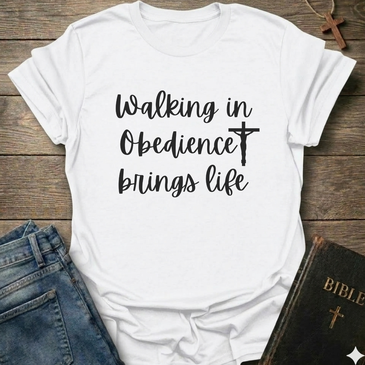 White t-shirt with 'Walking in Obedience brings life' text and cross graphic Christian script faith apparel conversation starter on a wooden surface.