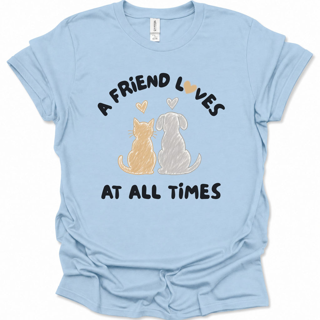 A light blue short-sleeve t-shirt with a graphic print of a cat and a dog sitting side by side under the text 'A FRIEND LOVES AT ALL TIMES'. The cat is orange and the dog is white, with small orange and white hearts above them.