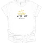 A white short-sleeve crewneck t-shirt with a graphic on the chest featuring a yellow sun and the text 'I AM THE LIGHT MATTHEW 5:14' in black, displayed on a clean white background.