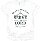 A white short-sleeve crewneck t-shirt with a dark green graphic print on the front. The graphic features a house silhouette with a cross, the words 'ME AND MY HOUSE' arched above, 'SERVE THE LORD' in large bold letters in the center, and '- JOSHUA 24:15 -' curved below.