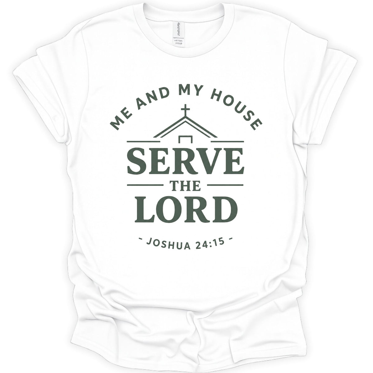 A white short-sleeve crewneck t-shirt with a dark green graphic print on the front. The graphic features a house silhouette with a cross, the words 'ME AND MY HOUSE' arched above, 'SERVE THE LORD' in large bold letters in the center, and '- JOSHUA 24:15 -' curved below.