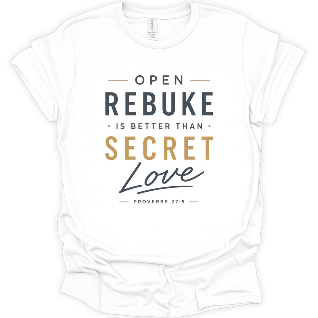 A white short-sleeve crewneck t-shirt with a printed graphic on the front. The text reads 'OPEN REBUKE IS BETTER THAN SECRET Love' with 'PROVERBS 27:5' underneath, using dark gray and gold typography.