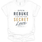 A white short-sleeve crewneck t-shirt with a printed graphic on the front. The text reads 'OPEN REBUKE IS BETTER THAN SECRET Love' with 'PROVERBS 27:5' underneath, using dark gray and gold typography.