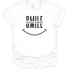 A white short-sleeve crewneck t-shirt with a black graphic print on the front reading 'SMILE JESUS CARES' and a smiley face, shown on a plain white background.