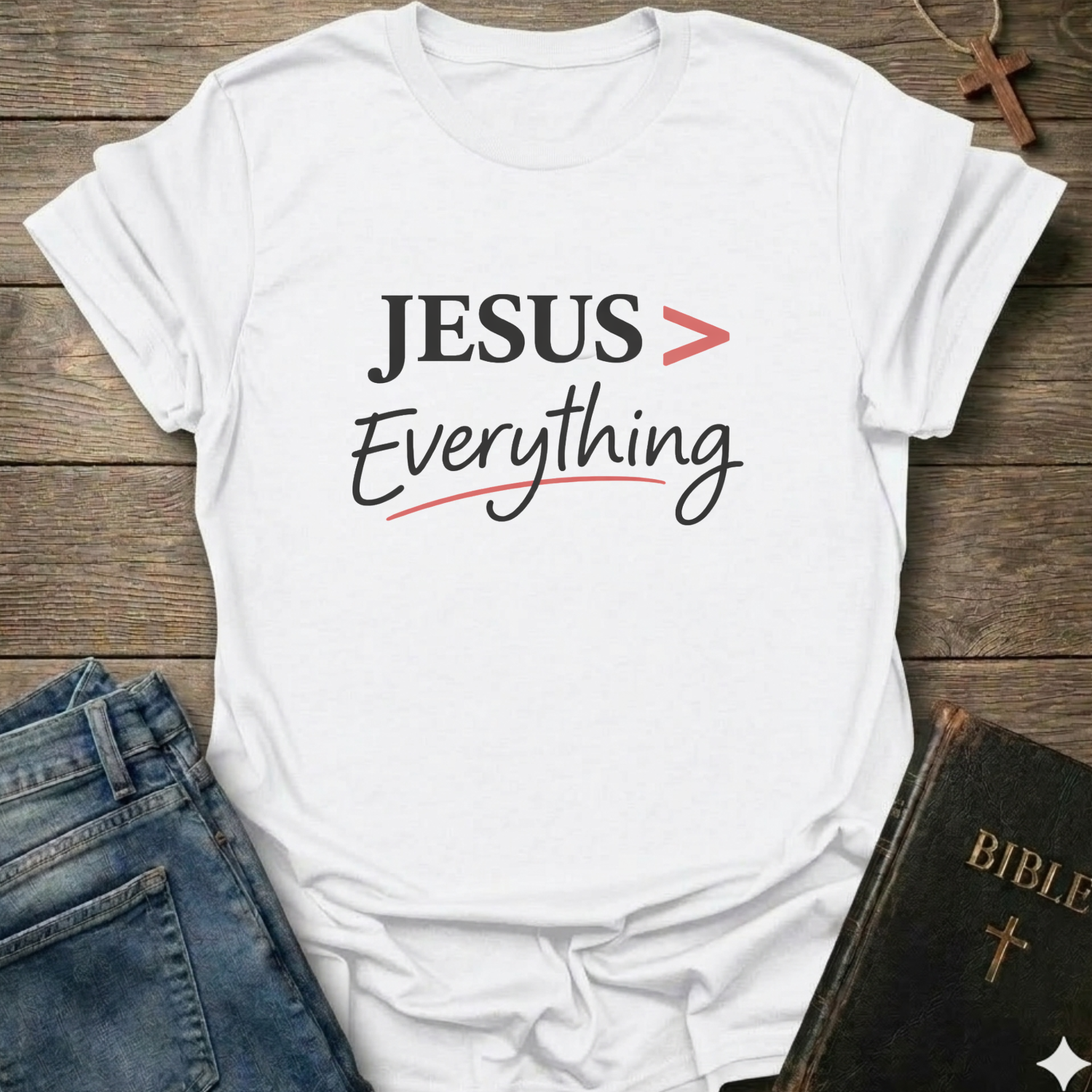 White T-Shirt faith apparel conversation starter with 'JESUS > Everything' text on a wooden surface with jeans and a Bible.
