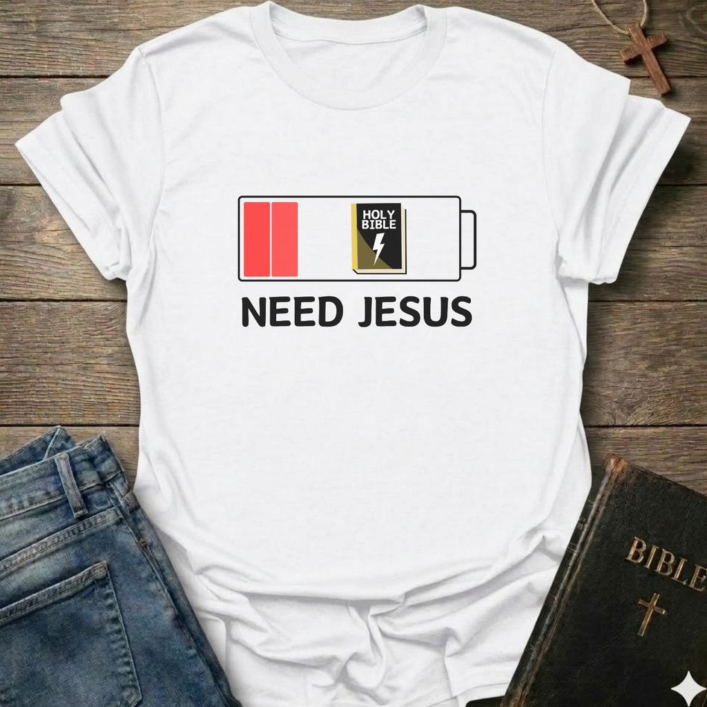 White t-shirt with 'Need Jesus' graphic on a wooden surface with a Bible and cross. Need Jesus to Recharge My Battery Christian T-Shirt bold faith apparel Faith Forward