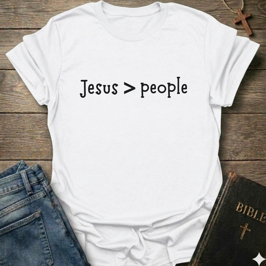 White t-shirt  'Jesus > people' Christian faith apparel conversation starter text on a wooden surface with jeans and a Bible.