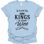 A light blue short-sleeve t-shirt with a black graphic print that reads 'It is not for KINGS to drink Wine' with a crown and two clinking wine bottles, shown on a plain white background.