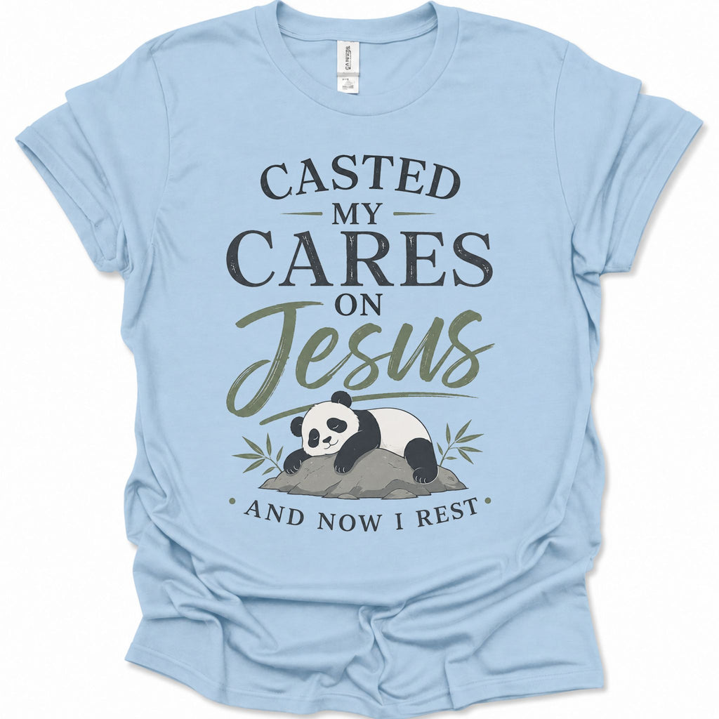A light blue short-sleeve t-shirt with a graphic print featuring a panda resting on a rock with the text 'CASTED MY CARES ON Jesus AND NOW I REST' in black and olive green lettering, accompanied by an illustration of a sleeping panda resting on a rock with bamboo leaves.