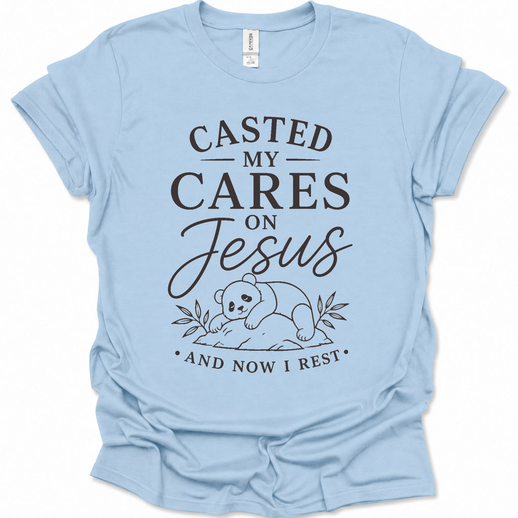 A light blue short-sleeve crewneck t-shirt with a black graphic print on the front. The text reads 'CASTED MY CARES ON Jesus AND NOW I REST' with a simple line drawing of a baby panda resting on a log.