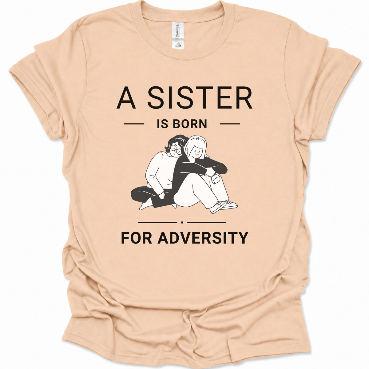 A natural-colored short-sleeve t-shirt with a black graphic print that reads 'A SISTER IS BORN FOR ADVERTS' surrounding an illustration of two people hugging. The shirt is laid flat on a white background.