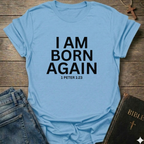 Light blue with 'I AM BORN AGAIN 1 PETER 1:23' text I Am Born Again Christian bold faith apparel conversation starter on a wooden surface with jeans and a Bible.