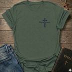 Military Green t-shirt with a blue cross and 'Redeemed' text Christian minimal faith apparel Faith Forward on a wooden surface with jeans and a Bible.