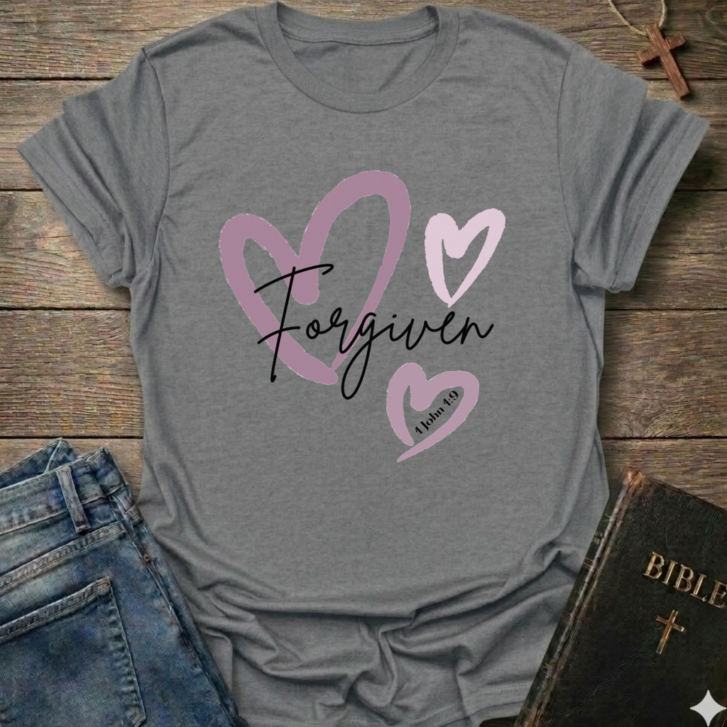 Gray t-shirt with 'Forgiven' text and pink hearts on a wooden surface with jeans and a Bible. Forgiven Christian T-Shirt 1 John 1:9 bold faith apparel Faith Forward women