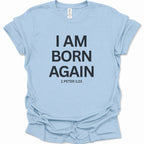 A light blue short-sleeve t-shirt with bold black text reading 'I AM BORN AGAIN' and '1 PETER 1:23' printed on the front, displayed flat against a white background.