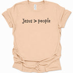 A light natural-colored short-sleeve t-shirt with the text 'Jesus > people' printed in black across the chest, displayed on a clean white background.