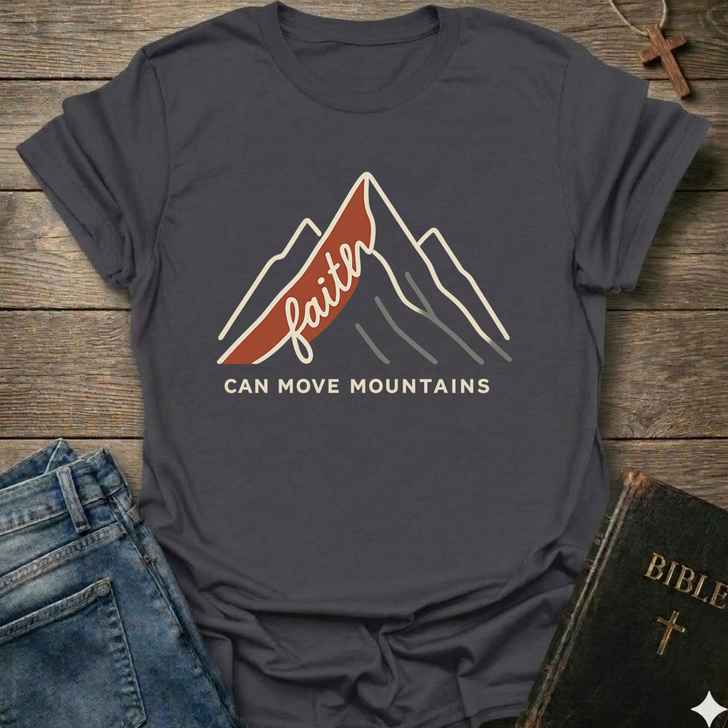 Gray Christian t-shirt with 'Faith can move mountains' graphic Matthew 17:20 faith apparel conversation starter on a wooden surface with jeans and a Bible. 