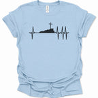 A light blue short-sleeve t-shirt with a black graphic of a heartbeat EKG line forming a cross on a hill, displayed flat against a white background.