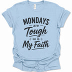 A light blue short-sleeve t-shirt with a black graphic text print reading 'MONDAYS are Tough so is My Faith' on a clean white background.
