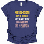 A purple blue short-sleeve t-shirt with a distressed typographic graphic on the front reading 'SHORT-TERM ON EARTH PREPARE FOR LONGTERM IN HEAVEN' in yellow, white, and pink lettering.