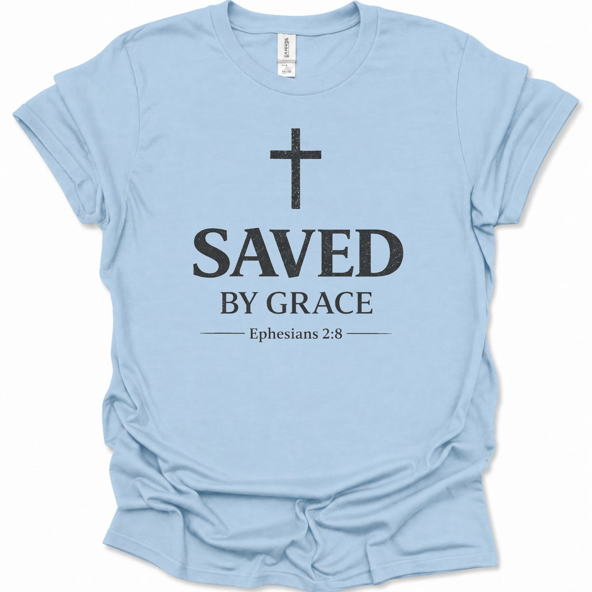 A light blue short-sleeve crewneck t-shirt with a distressed black graphic print on the front featuring a cross, the text 'SAVED BY GRACE', and 'Ephesians 2:8'.