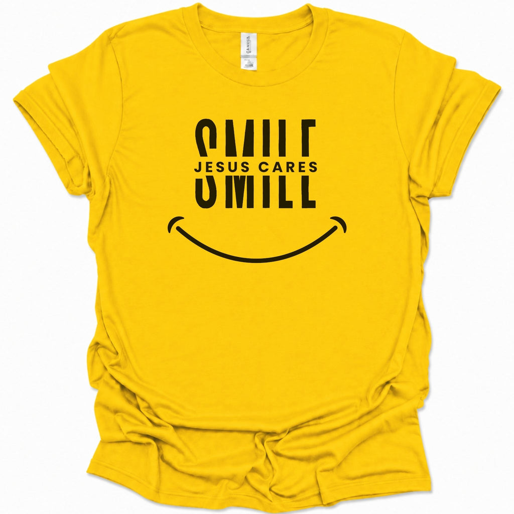 A daisy yellow short-sleeve t-shirt with a black graphic print on the front that reads 'SMILE JESUS CARES' above a smiley face, shown on a clean white background.