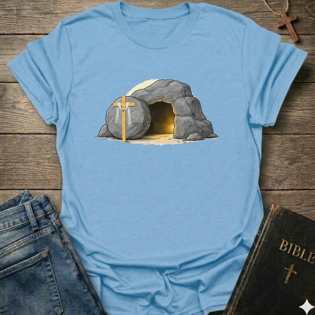 Blue t-shirt with a graphic of a  Empty Tomb and a cross Christian resurrection faith apparel conversation starter on a wooden surface with jeans and a Bible.