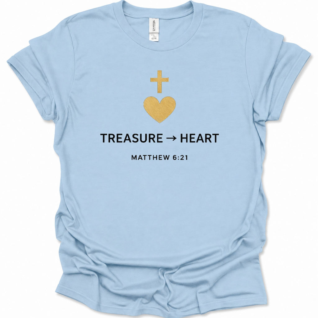 A light blue short-sleeve t-shirt with a graphic on the chest featuring a gold heart and cross, the text 'TREASURE -> HEART', and 'MATTHEW 6:21' in black. The shirt is shown flat against a white background.
