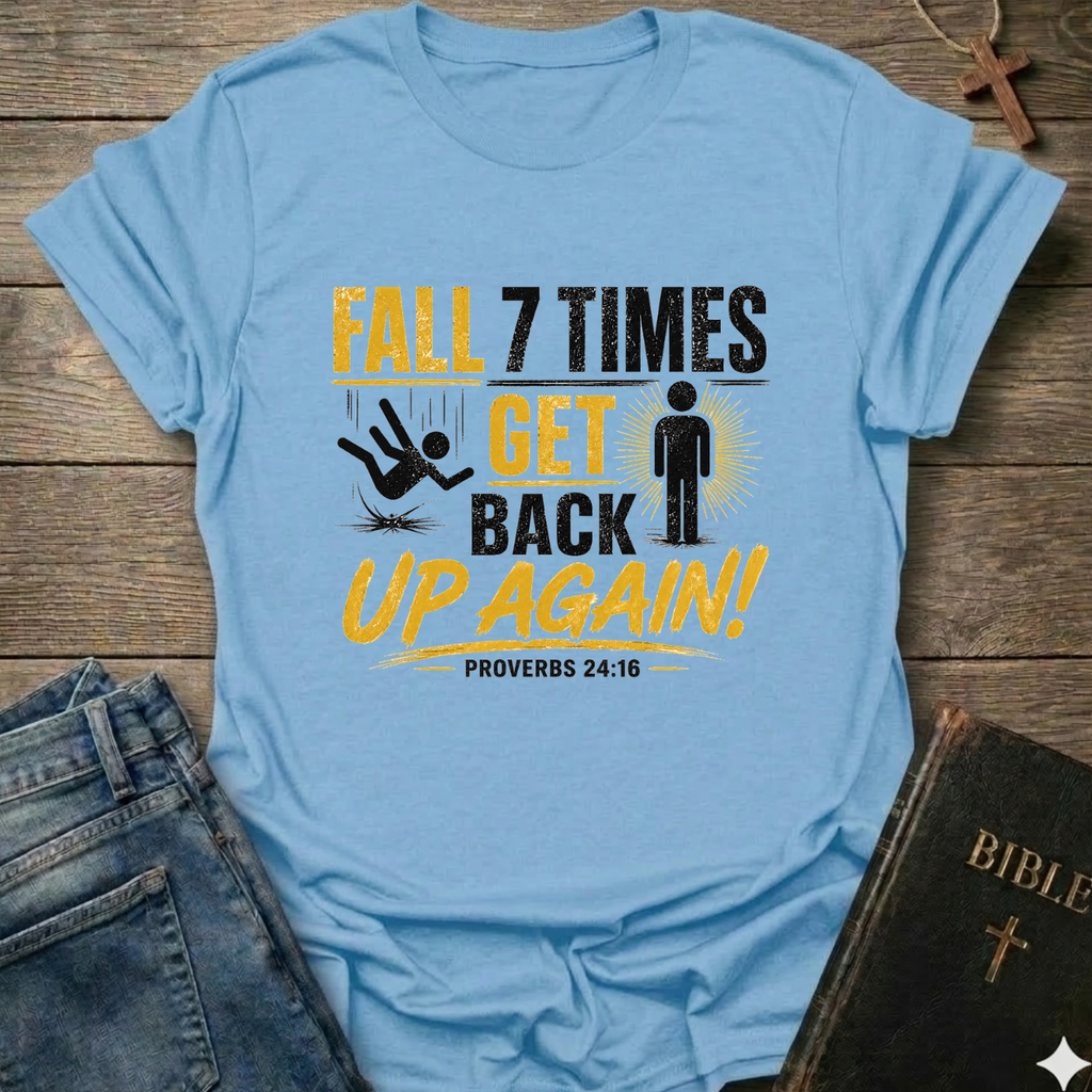Light blue t-shirt with motivational quote "Fall 7 Times Get Back Up Again Proverbs 24:16" bold graphic faith apparel Faith Forward on a wooden surface with jeans and a Bible.