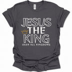 A dark heather gray short-sleeve t-shirt with a graphic print that reads 'JESUS THE KING OVER ALL KINGDOMS' in white outline lettering, accented by a small gold crown icon, shown on a plain white background.