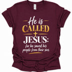 A maroon short-sleeve t-shirt with a graphic print on the front that reads 'He is CALLED JESUS: for he saved his people from their sins.' in white and gold lettering, displayed on a clean white background.