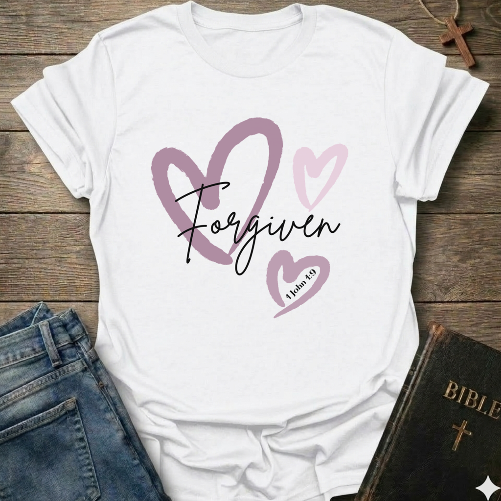 White t-shirt with 'Forgiven' text and pink hearts on a wooden surface with jeans and a Bible. Forgiven Christian T-Shirt 1 John 1:9 bold faith apparel Faith Forward women