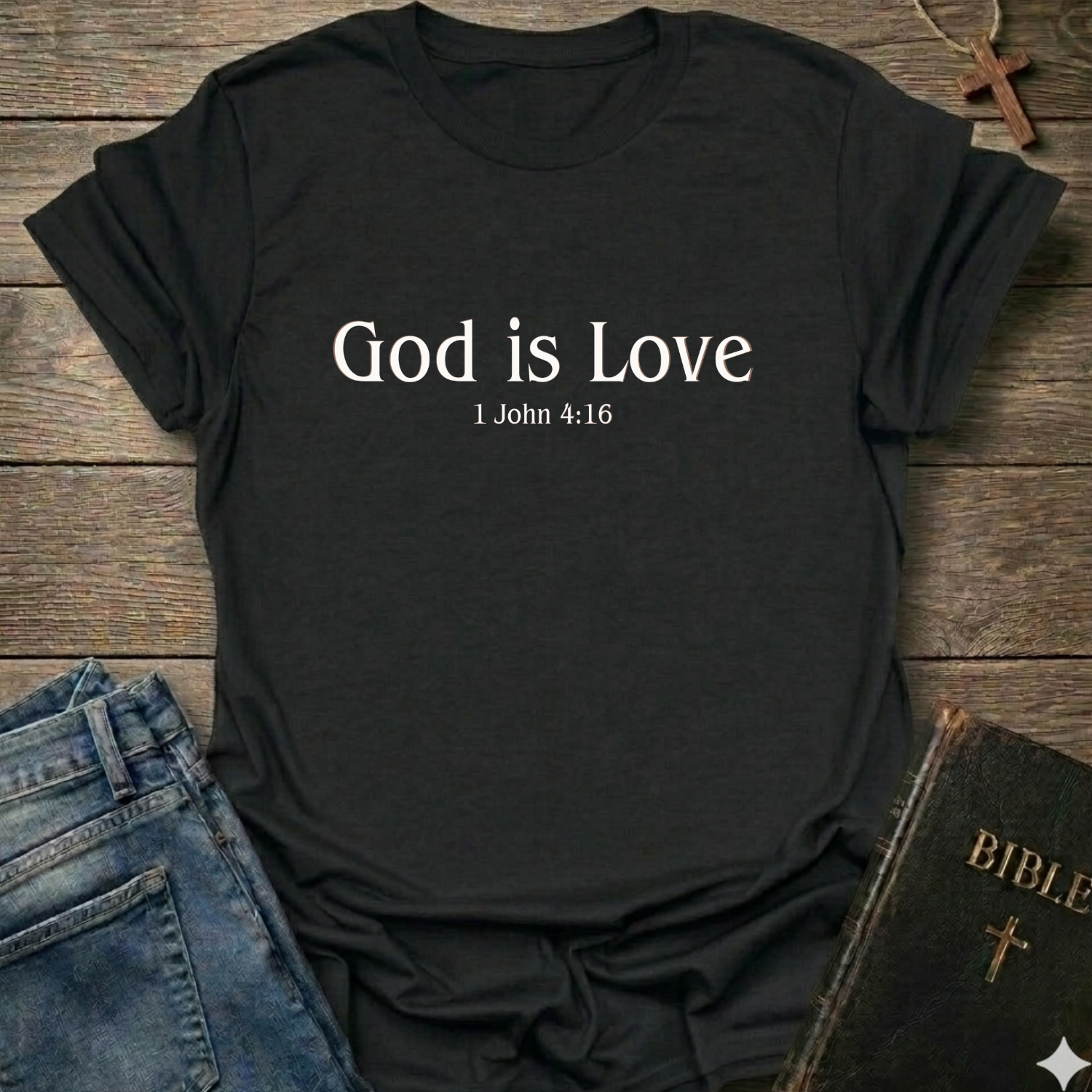 Black t-shirt with 'God is Love'  Christian T-Shirt 1 John 4:15 elegant faith apparel Faith Forward text. T-shirt on a wooden surface with jeans and a Bible.