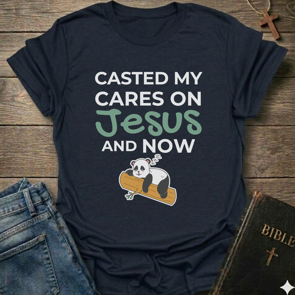 Black t-shirt Casted My Cares on Jesus Christian relatable faith apparel conversation starter with a panda graphic and text on a wooden surface with jeans and a Bible.