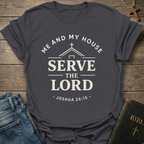 Gray t-shirt with Me and My House Serve the Lord | Joshua 24:15 Faith Forward text on a wooden surface with jeans and a Bible.