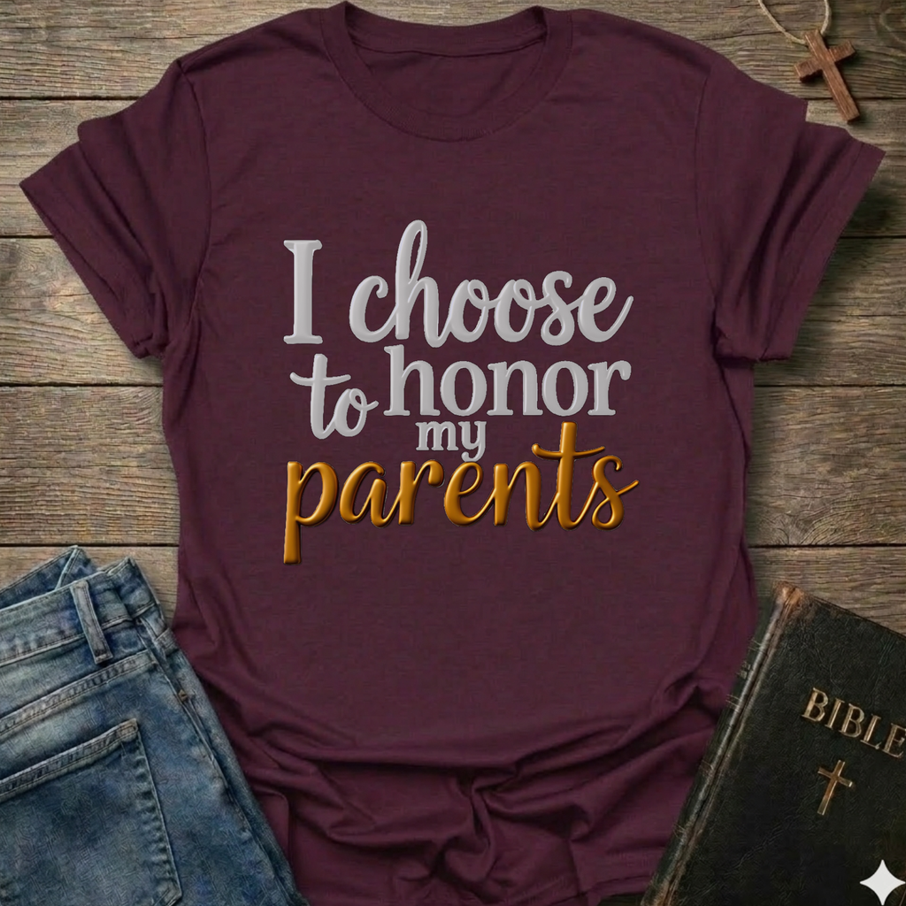 Maroon t-shirt with 'I choose to honor my parents' Exodus 20:12 text navy gold Christian faith apparel conversation starter. T-shirt is on a wooden surface with jeans and a Bible.