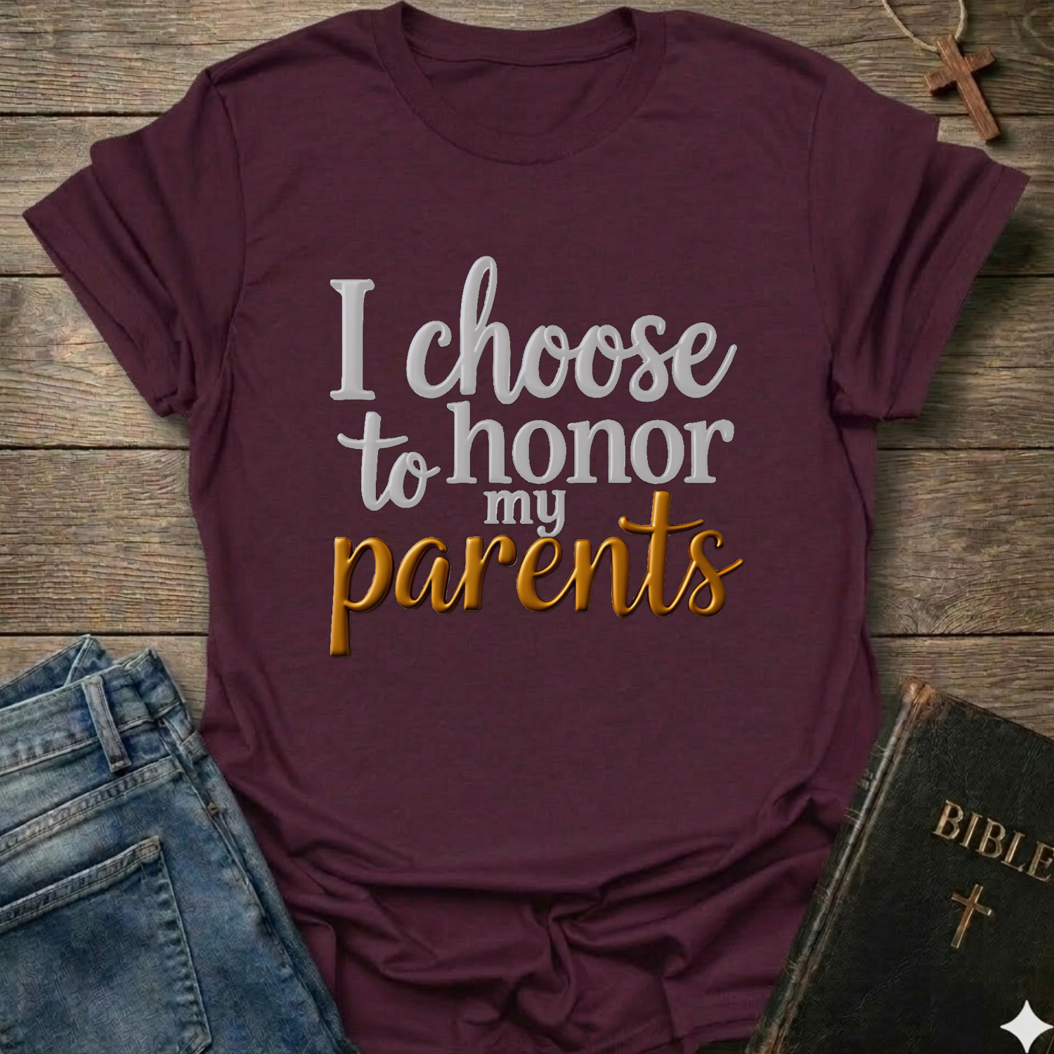 Maroon t-shirt with 'I choose to honor my parents' Exodus 20:12 text navy gold Christian faith apparel conversation starter. T-shirt is on a wooden surface with jeans and a Bible.