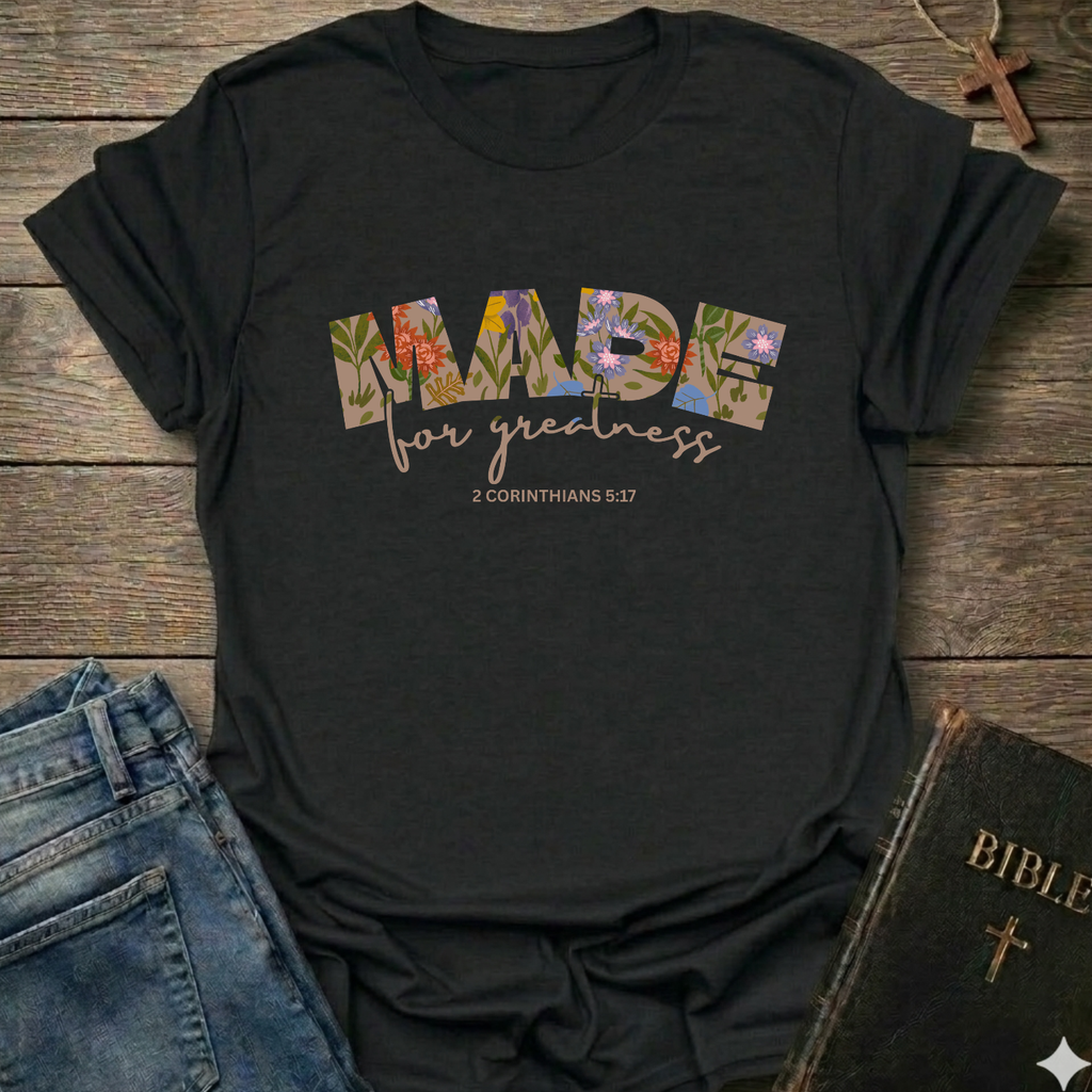 Black t-shirt with 'Made for greatness' text on a wooden surface with jeans and a Bible. Made for Greatness Christian T-Shirt 2 Corinthians 5:17 bold faith apparel Faith Forward women