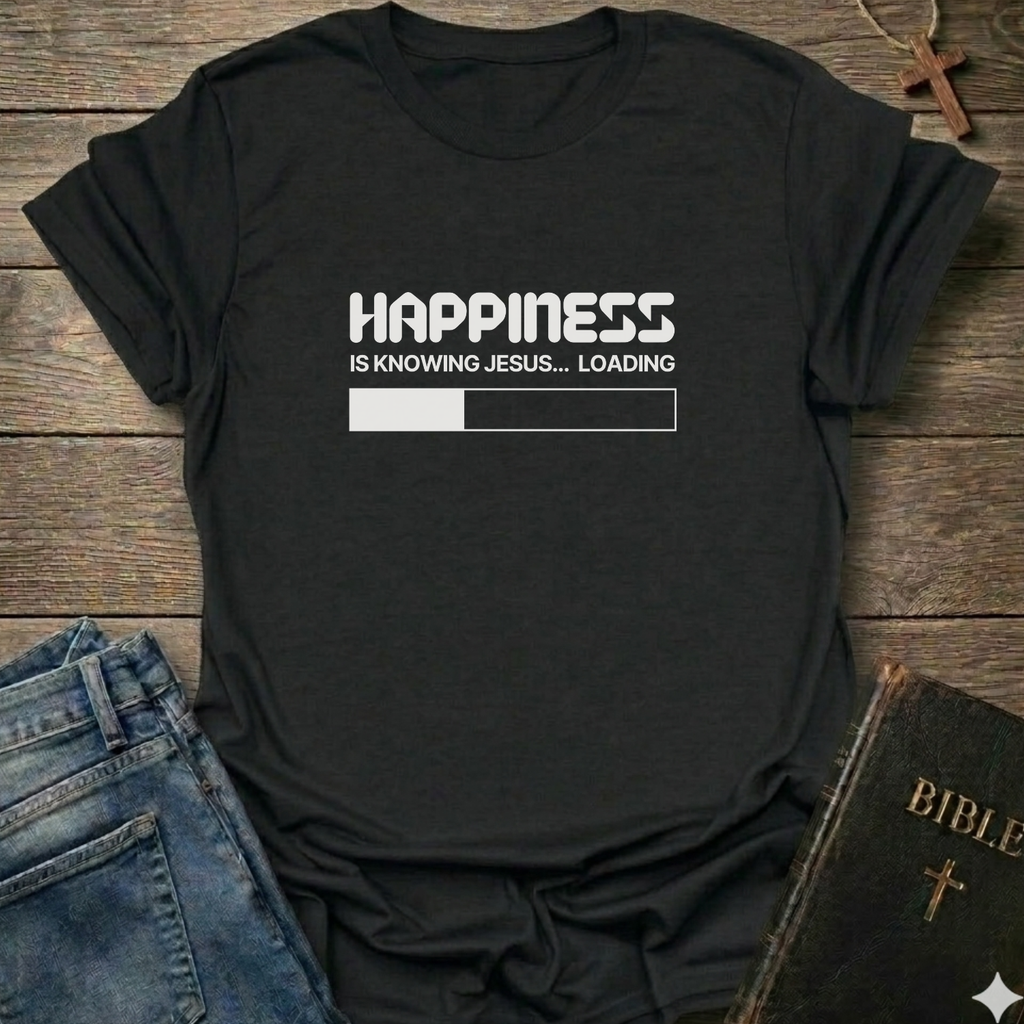 A black graphic t-shirt laid flat  on a rustic wooden surface, styled with blue jeans and a black Bible. The t-shirt features a white printed loading bar "like a battery charging" graphic that reads 'HAPPINESS IS KNOWING JESUS.