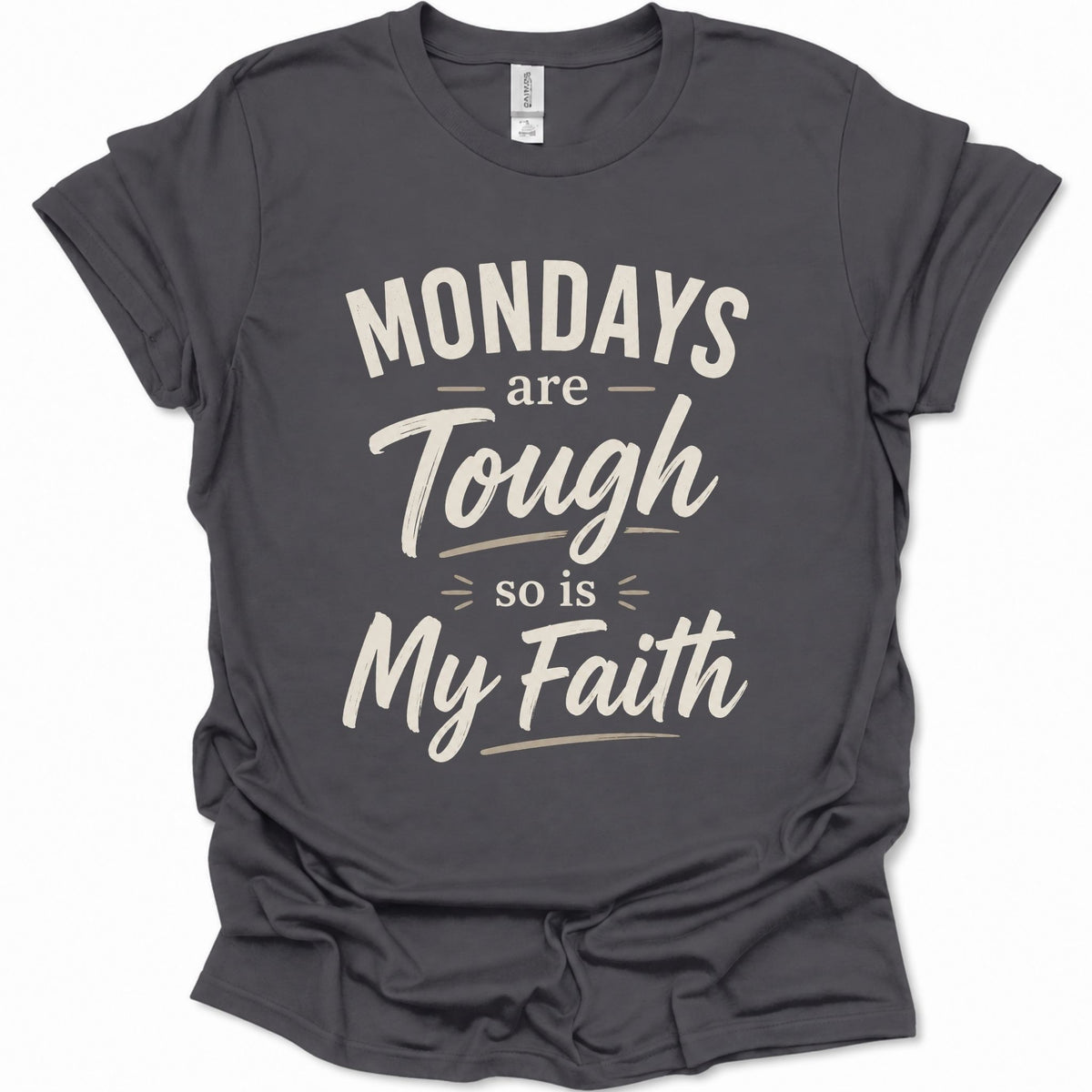 A dark heather gray short-sleeve t-shirt with a distressed cream-colored graphic text that reads 'MONDAYS are Tough so is My Faith'. The t-shirt is displayed flat against a clean white background.