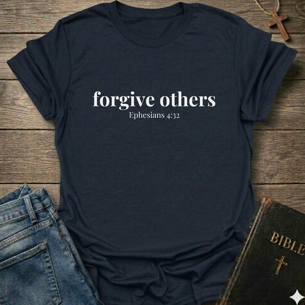 Navy blue t-shirt with 'forgive others Ephesians 4:32' text on a wooden surface with jeans and a Bible.