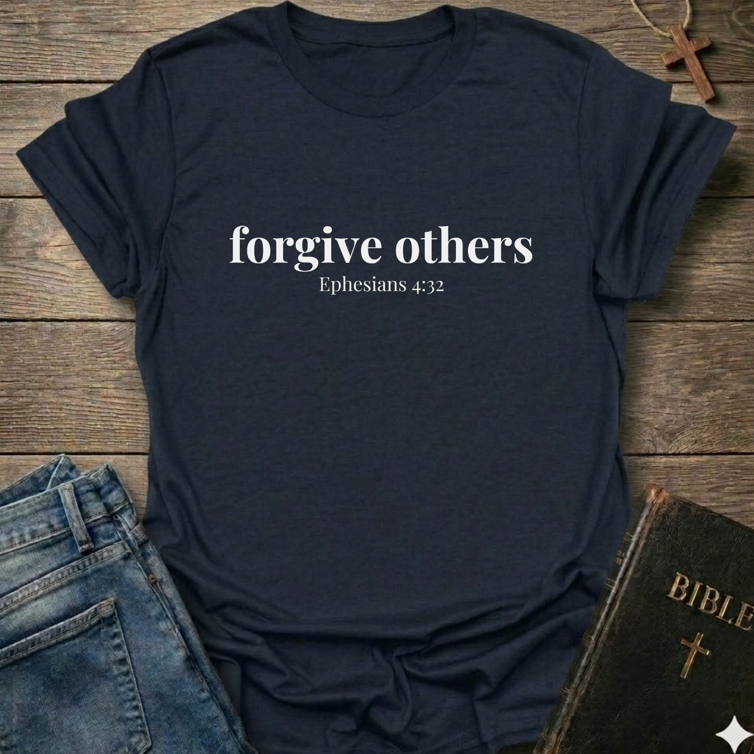 Navy blue t-shirt with 'forgive others Ephesians 4:32' text on a wooden surface with jeans and a Bible.