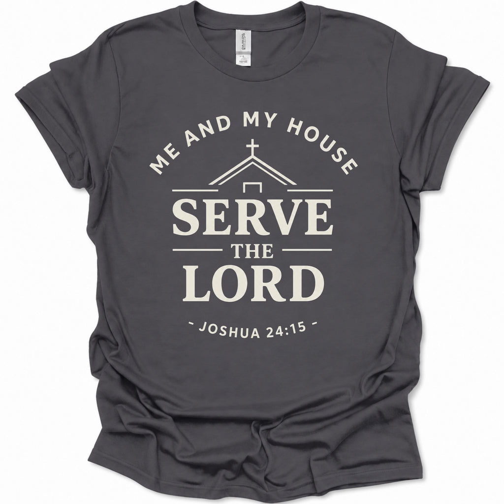 A dark heather gray short-sleeve t-shirt with a cream-colored graphic print that reads 'ME AND MY HOUSE SERVE THE LORD - JOSHUA 24:15' with a house silhouette and cross.