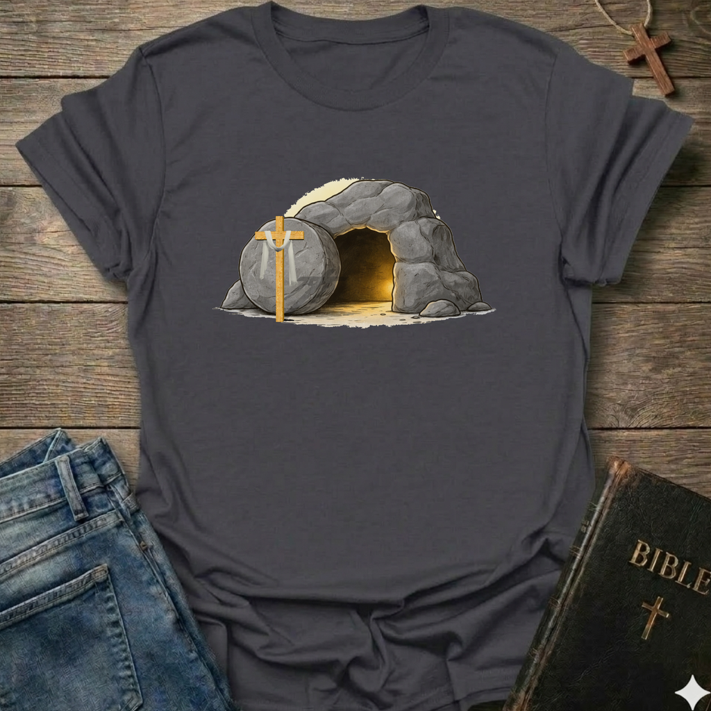 Dark gray t-shirt with a graphic of a  Empty Tomb and a cross Christian resurrection faith apparel conversation starter on a wooden surface with jeans and a Bible.