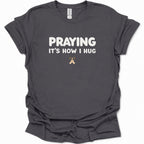 A dark heather gray short-sleeve t-shirt with a graphic on the chest showing four square icons: a Christian cross, an anchor, a heart, and a dove, all in a muted blue-gray color.