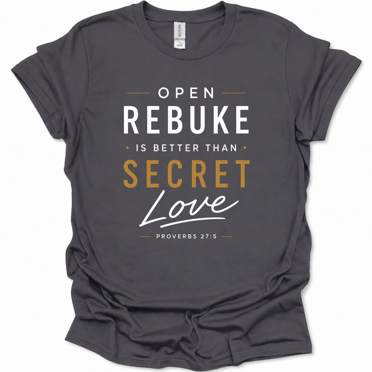A dark heather gray graphic t-shirt featuring the text 'OPEN REBUKE IS BETTER THAN SECRET Love' and 'PROVERBS 27:5' in white and gold lettering, displayed on a clean white background.