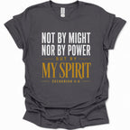 A dark heather gray short-sleeve t-shirt with a printed Bible verse on the front reading 'NOT BY MIGHT NOR BY POWER BUT BY MY SPIRIT ZECHARIAH 4:6' in white and mustard yellow text, shown on a plain white background.